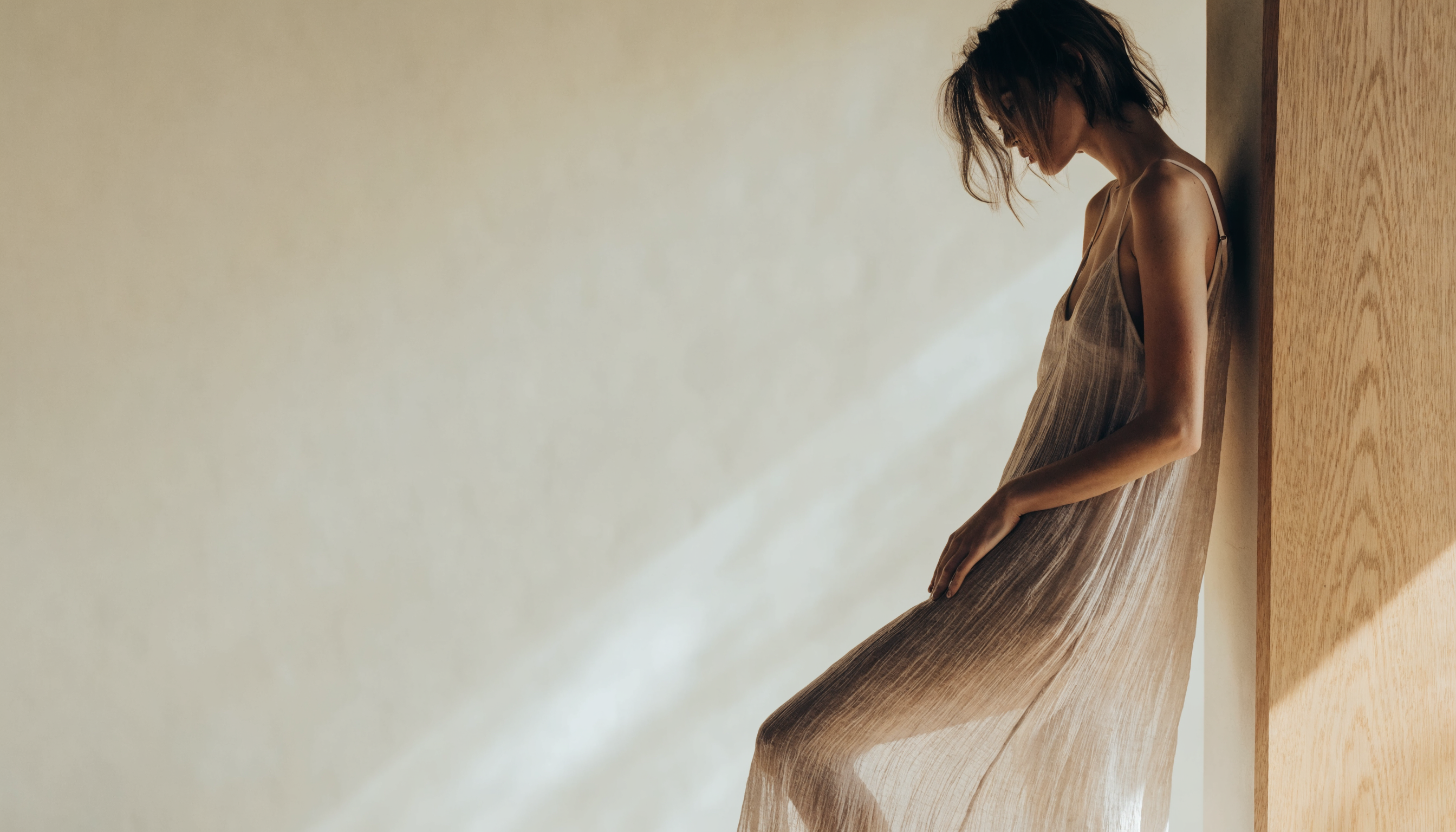 Woman in a flowing neutral cami maxi dress in warm natural daylight